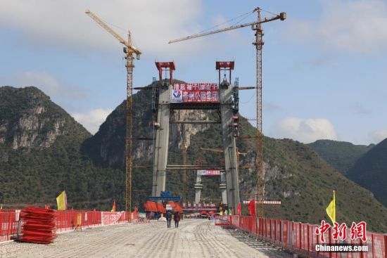 11月22日，正在建設(shè)中的峰林特大橋。當(dāng)日，隨著1470噸裝配化預(yù)制中橫梁提升到位，貴州省黔西南布依族苗族自治州興義環(huán)城高速公路峰林特大橋4號主塔中橫梁成功吊裝，由此刷新了山區(qū)峽谷橋梁預(yù)制吊裝混凝土構(gòu)件重量世界記錄。峰林特大橋是屬全線控制性工程。大橋跨越馬嶺河峽谷，全長1163米，主跨采用550米懸索橋，橋面離谷底364.2米，是中國山區(qū)第一座大跨徑鋼混疊合梁懸索橋。中新社記者 瞿宏倫 攝