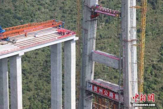 11月22日，峰林特大橋4號主塔中橫梁正在吊裝。當(dāng)日，隨著1470噸裝配化預(yù)制中橫梁提升到位，貴州省黔西南布依族苗族自治州興義環(huán)城高速公路峰林特大橋4號主塔中橫梁成功吊裝，由此刷新了山區(qū)峽谷橋梁預(yù)制吊裝混凝土構(gòu)件重量世界記錄。峰林特大橋是屬全線控制性工程。大橋跨越馬嶺河峽谷，全長1163米，主跨采用550米懸索橋，橋面離谷底364.2米，是中國山區(qū)第一座大跨徑鋼混疊合梁懸索橋。中新社記者 瞿宏倫 攝