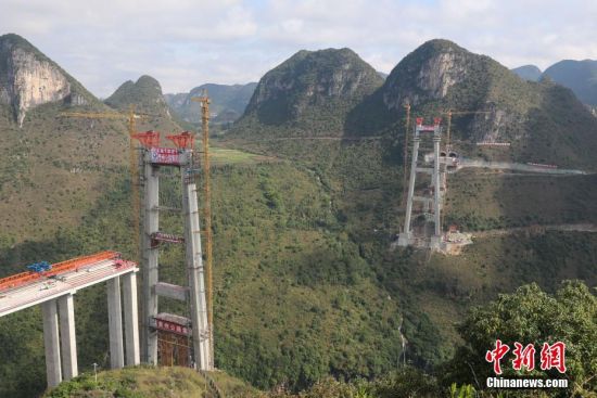 11月22日，正在建設(shè)中的峰林特大橋。當(dāng)日，隨著1470噸裝配化預(yù)制中橫梁提升到位，貴州省黔西南布依族苗族自治州興義環(huán)城高速公路峰林特大橋4號主塔中橫梁成功吊裝，由此刷新了山區(qū)峽谷橋梁預(yù)制吊裝混凝土構(gòu)件重量世界記錄。峰林特大橋是屬全線控制性工程。大橋跨越馬嶺河峽谷，全長1163米，主跨采用550米懸索橋，橋面離谷底364.2米，是中國山區(qū)第一座大跨徑鋼混疊合梁懸索橋。中新社記者 瞿宏倫 攝