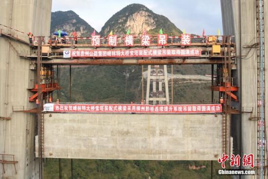 11月22日，隨著1470噸裝配化預(yù)制中橫梁提升到位，貴州省黔西南布依族苗族自治州興義環(huán)城高速公路峰林特大橋4號主塔中橫梁成功吊裝，由此刷新了山區(qū)峽谷橋梁預(yù)制吊裝混凝土構(gòu)件重量世界記錄。峰林特大橋是屬全線控制性工程。大橋跨越馬嶺河峽谷，全長1163米，主跨采用550米懸索橋，橋面離谷底364.2米，是中國山區(qū)第一座大跨徑鋼混疊合梁懸索橋。中新社記者 瞿宏倫 攝